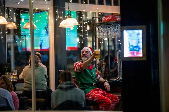 A man dressed as a Christmas elf enjoying a pint outside a pub in the south of the city of London, United Kingdom on December 15, 2021. (Photo by Jill Mead/The Guardian)