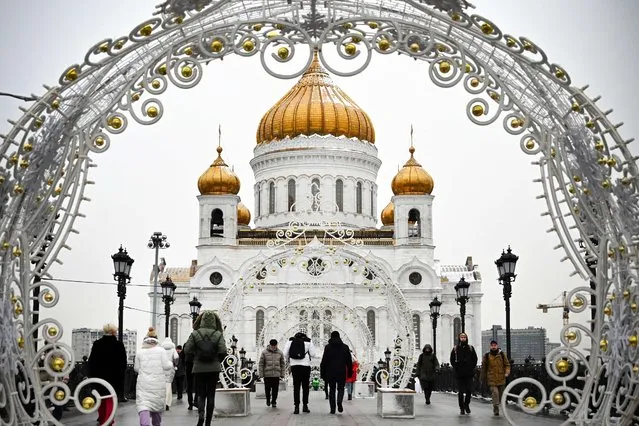 Pedestrians walk through the Christmas decorations in front of Christ the Saviour cathedral, the main Russian Orthodox church, in Moscow, on December 2, 2021. (Photo by Alexander Nemenov/AFP Photo)