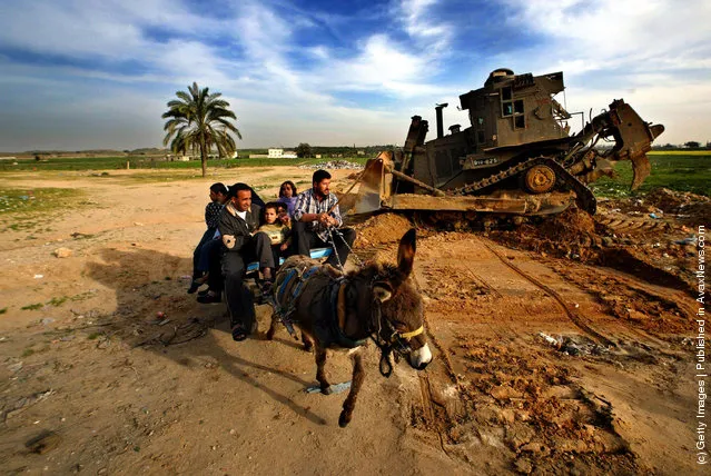 A Palestinian family in a donkey cart passes by an Israeli bulldozer on the Palestinian side of the Erez Crossing