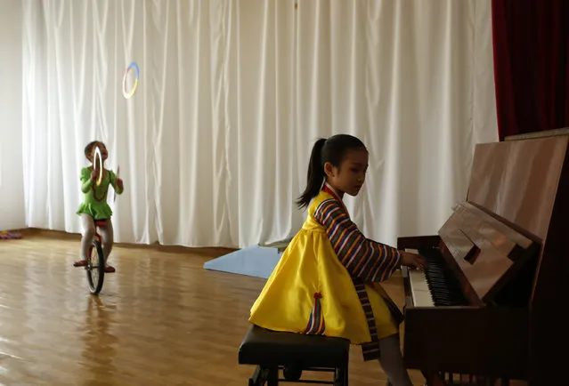 A North Korean girl plays the piano while the other on unicycles performs at the Kaeson Kindergarden in Pyongyang, North Korea Tuesday, April 24, 2012. (Photo by Vincent Yu/AP Photo)