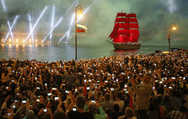 People watch fireworks and a brig with scarlet sails floating on the Neva River during the Scarlet Sails festivities marking school graduation in St.Petersburg, Russia, early Monday, June 24, 2019. This week graduation ceremonies and celebrations are held all over Russia as students of elementary and high schools and military academies finished their education. (Photo by Dmitri Lovetsky/AP Photo)