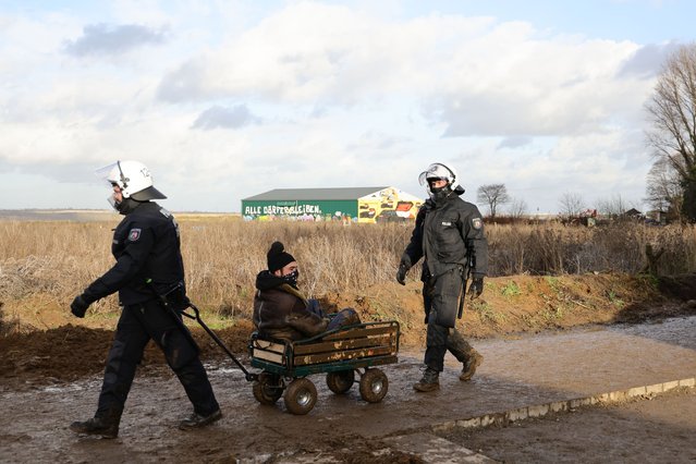 Police carry away activists at the settlement of Luetzerath next to the Garzweiler II open cast coal mine on January 11, 2023 near Erkelenz, Germany. Police are evicting environmental activists who have occupied the abandoned Luetzerath settlement and are seeking to prevent Luetzerath's demolition that will make way for an expansion of the Garzweiler coal mine. The North Rhine-Westphalia state government of German Christian Democrats (CDU) and Greens has approved the demolition and the coal mine expansion, while at the same time announcing an accelerated phase out of coal-fired energy production in the state of North Rhine-Westphalia from 2038 to 2030. Other nearby settlements that were also slated for demolition will now be spared, though critics point out that Germany has sufficient energy production capacity and does not need the coal lying beneath Luetzerath. (Photo by Andreas Rentz/Getty Images)