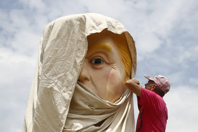 A protester unwraps a sculpture depicting President Donald Trump holding a cell phone on a toilet before Independence Day celebrations, Thursday, July 4, 2019, on the National Mall in Washington. (Photo by Patrick Semansky/AP Photo)