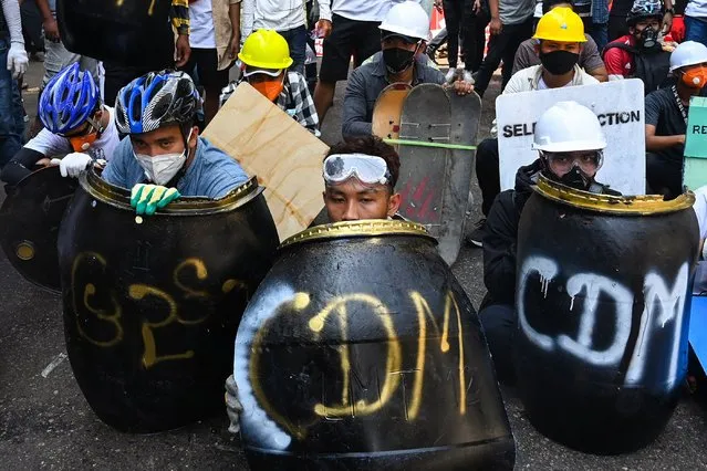 Protesters take cover behind homemade shields during a demonstration against the military coup in Yangon on February 28, 2021. (Photo by Sai Aung Main/AFP Photo)