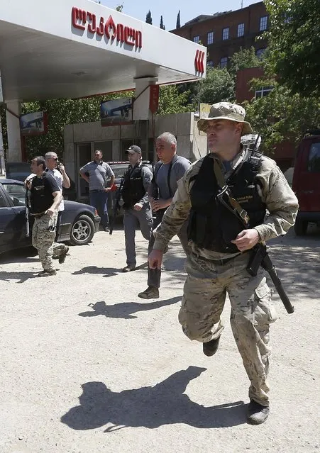 Armed policemen run after police killed a white tiger that had escaped from its enclosure during flooding, in Tbilisi, Georgia, June 17, 2015. Tigers, lions, bears and wolves were among more than 30 animals that escaped from a Georgian zoo and onto the streets of the capital Tbilisi on Sunday during floods that killed at least 12 people. REUTERS/David Mdzinarishvili