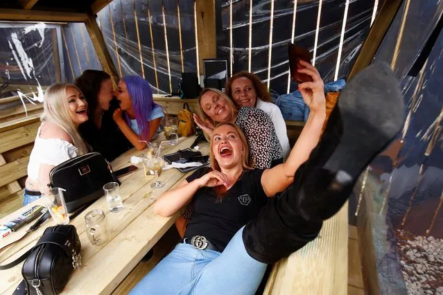 Customers at The Swinging Witch pub pose for a selfie while they enjoy drinks, as lockdown eases amid the coronavirus disease (COVID-19) pandemic, in Northwich, Cheshire, Britain, May 15, 2021. (Photo by Jason Cairnduff/Reuters)