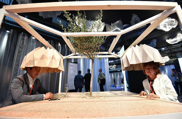 Visitors sit at a table presented during the “Salone del Mobile” trade fair in Rho-Pero, near Milan, Italy, 04 April 2017. The fair, considered the largest of its kind in the world, presents the latest trends and designs on furniture, lighting and home accessories from 04 to 09 April. (Photo by Daniel Dal Zennaro/EPA)