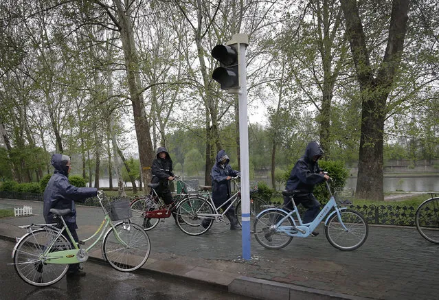 North Koreans push their bicycles in the rain on a pathway along the Pothong River at the end of a work day on Thursday, May 5, 2016, in Pyongyang, North Korea. (Photo by Wong Maye-E/AP Photo)