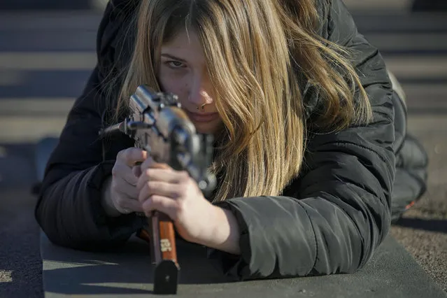 A young woman holds a weapon during a basic combat training for civilians, organized by the Special Forces Unit Azov, of Ukraine's National Guard, in Mariupol, Donetsk region, eastern Ukraine, Sunday, February 13, 2022. The United States is evacuating almost all of the staff from its embassy in Kyiv as Western intelligence officials warn that a Russian invasion of Ukraine is increasingly imminent. (Photo by Vadim Ghirda/AP Photo)