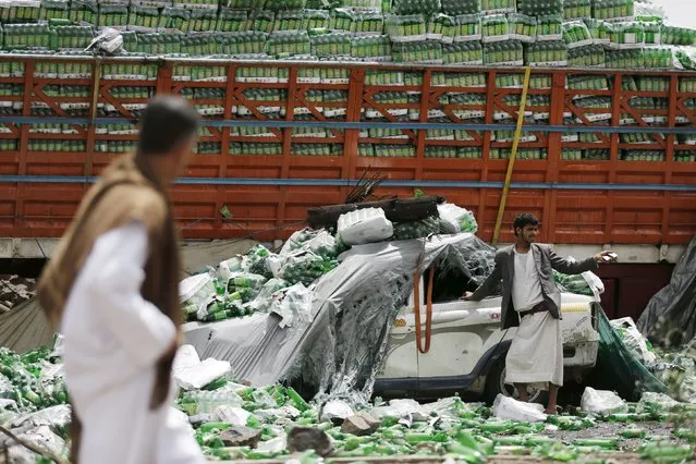 People stand near bottled drinks which have fallen off a truck damaged by a Saudi-led air strike in Yemen's capital Sanaa July 14, 2015. A Saudi-led Arab coalition has been bombarding the Iranian-allied Houthi rebel movement – Yemen's dominant force – since late March in a bid to reinstate exiled President Abd-Rabbu Mansour Hadi, who has fled to Riyadh. (Photo by Khaled Abdullah/Reuters)