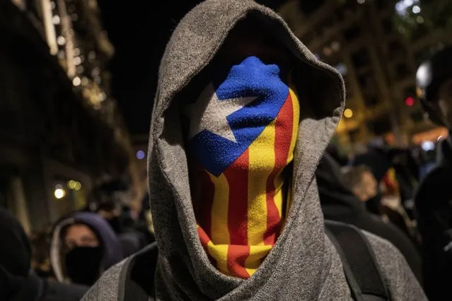 A protester wearing an Estelada or Catalan independence mask stands in front police, not seen, moments before clashes in Barcelona, Saturday, October 26, 2019. The clash comes after 350,000 people protested peacefully Saturday against the imprisonment of nine Catalan separatist leaders for their roles in an illegal 2017 secession bid. (Photo by Bernat Armangue/AP Photo)