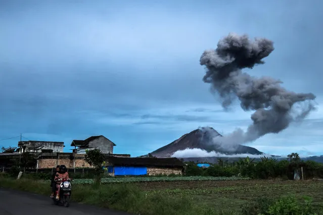 Motorists ride along a road as Mount Sinabung volcano spews thick volcanic ash, as seen from Tangkulen village in Karo, on May 12, 2017. Sinabung roared back to life in 2010 for the first time in 400 years. After another period of inactivity, it erupted once more in 2013 and has remained highly active since. (Photo by Tibta Pangin/AFP Photo)