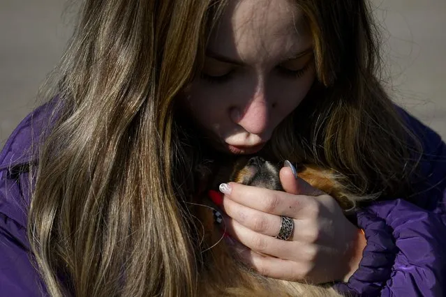 A refugee fleeing the war from neighbouring Ukraine kisses a small dog after crossing the border, at the Romanian-Ukrainian border, in Siret, Romania, Monday, March 14, 2022. (Photo by Andreea Alexandru/AP Photo)