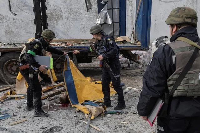 Ukrainian policemen cover a man killed in a missile strike in Kramatorsk, Donetsk region, Ukraine on April 19, 2022. (Photo by Marko Djurica/Reuters)