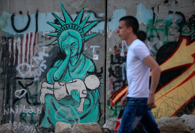 A Palestinian walks past graffiti painted on the controversial Israeli barrier in the West Bank town of Bethlehem, April 27, 2016. (Photo by Ammar Awad/Reuters)