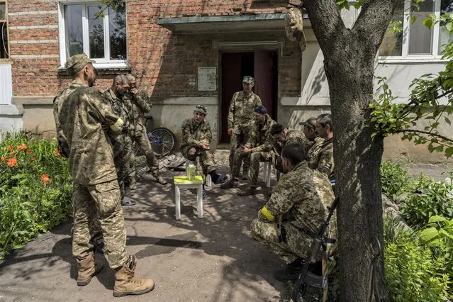 Ukrainian Territorial Defence Force members chat during a deployment break after returning from the frontline in the Kharkiv area, eastern Ukraine, on Monday, May 30, 2022. (Photo by Bernat Armangue/AP Photo)