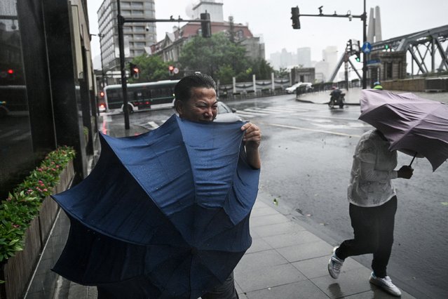 Pedestrians struggle with their umbrellas in strong winds and rain from the passage of Typhoon Bebinca in Shanghai on September 16, 2024. The strongest storm to hit Shanghai in over 70 years made landfall on September 16, state media reported, with flights cancelled and highways closed as Typhoon Bebinca lashed the city with strong winds and torrential rains. (Photo by Hector Retamal/AFP)