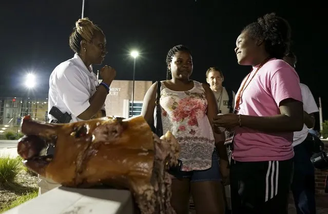 Ferguson police Sgt. Dominica Fuller (L) talks with protesters outside the police department with a pig's head from a pig roast placed on a wall separating them in Ferguson, Missouri August 8, 2015. (Photo by Rick Wilking/Reuters)