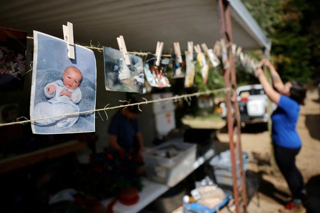 A person helps wash and dry photographs that were submerged in flood waters at the home of people impacted by Hurricane Helene, in Cruso, North Carolina on October 3, 2024. (Photo by Jonathan Drake/Reuters)