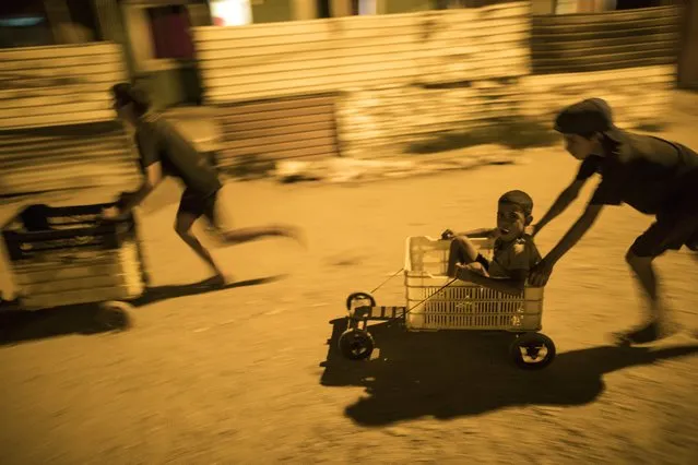 In this November 19, 2019 photo, children race in makeshift go-carts in the “Altos de Milagros Norte” neighborhood of Maracaibo, Venezuela. Nationwide, an estimated 4.5 million residents have fled Venezuela, most going to nearby Colombia, Peru and Ecuador. They search for better jobs to send money home, but they often confront backlash and hardships as their numbers steadily grow. (Photo by Rodrigo Abd/AP Photo)
