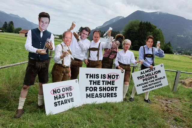 Activists of the NGO ONE, wearing masks depicting G7 leaders, protest against the G7 summit to be held in the nearby Bavarian alpine resort hotel Elmau Castle, outside the main G7 media centre, in Garmisch-Partenkirchen, Germany on June 24, 2022. (Photo by Wolfgang Rattay/Reuters)