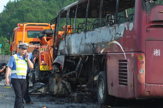 Police stand next to a burnt bus after a fire which killed at least 35 people in Yizhang county, Hunan province, China, June 26, 2016. (Photo by Reuters/Stringer)