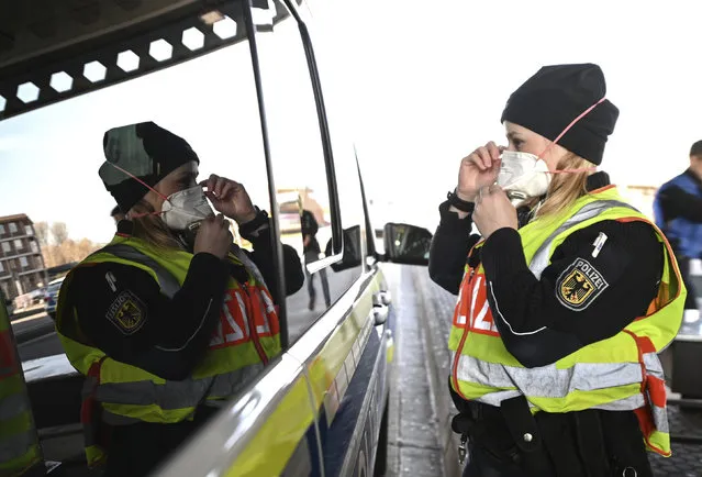 A female federal police officer puts on a breathing mask at the border crossing to Switzerland before an inspection in Weil am Rhein, Monday, march 16, 2020. In the wake of the coronavirus crisis, Germany will introduce comprehensive controls and entry bans at its borders with Switzerland. For most people, the new coronavirus causes only mild or moderate symptoms, such as fever and cough. For some, especially older adults and people with existing health problems, it can cause more severe illness, including pneumonia. (Photo by Patrick Seeger/dpa via AP Photo)