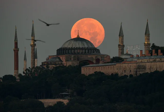 Full moon rises over the Hagia Sophia Grand Mosque and Blue Mosque in Istanbul, Turkiye on July 14, 2022. (Photo by Ali Atmaca/Anadolu Agency via Getty Images)