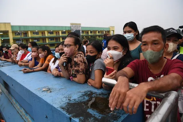 Parents watch from a pedestrian overpass as they observe their children during the opening of classes at a school in Quezon City, suburban Manila on August 22, 2022 as millions of children in the Philippines returned to school as the academic year started on August 22, with many taking their seats in classrooms for the first time since the Covid-19 pandemic hit. (Photo by Ted Aljibe/AFP Photo)