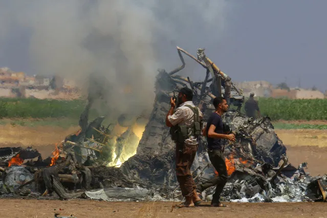 Men inspect the wreckage of a Russian helicopter that had been shot down in the north of Syria's rebel-held Idlib province, Syria August 1, 2016. The Mi-8 helicopter was shot down while returning to the Russian air base on Syria's coast after delivering humanitarian goods to the city of Aleppo, the Defense Ministry said in a statement. The helicopter had three crew members and two officers deployed with the Russian center at the Hemeimeem air base on the Syrian coast. (Photo by Ammar Abdullah/Reuters)