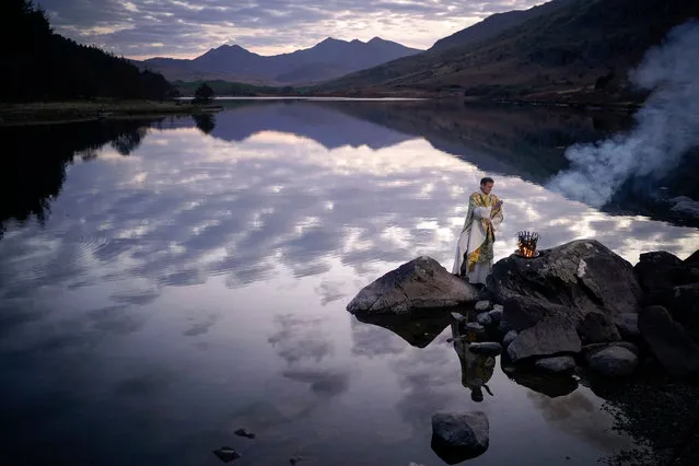 The Reverend Stuart Elliott blesses the new fire as part of his Service of New Light for Easter Eve on the shore of Llyn Mymbyr in Snowdonia on April 08, 2020 in Capel Curig, Wales. Rev Elliott is continuing his outdoor tradition of blessing the new fire for the 14th year. Without his parishioners to accompany him due to the coronavirus lockdown he has filmed various outdoor ceremonies which will be broadcast online for his flock to celebrate Easter. Reverend Elliott's Service of Light for Easter Eve normally begins with lighting a fire at a rural location, candles are then lit from the flames and in procession taken to the church to bathe it in the new light. Rev Elliott is regarded as a pioneer of outdoor worship and speaks on ecological issues for the Church in Wales. Many religious services are being recorded or live-streamed after the government banned large gatherings as part of its lockdown measures to halt the spread of the COVID-19 virus. (Photo by Christopher Furlong/Getty Images)