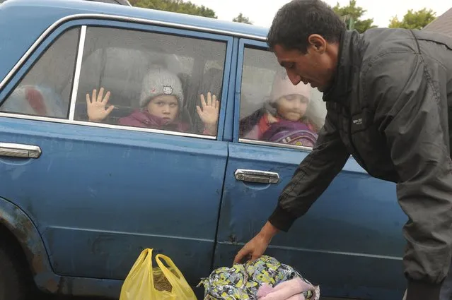 Children look through a car windows as they and other refugees from the Kharkov Region of Ukraine as they arrive at temporary camp in Belgorod, Russia, Wednesday, September 14, 2022. Thousands fled fled northeastern Ukraine to Russia amid Ukrainian counteroffensive in the region. (Photo by AP Photo/Stringer)