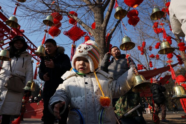A child stands amid bells and red lanterns decorating a temple fair, on the first day of the Lunar New Year, in Beijing, China on January 29, 2025. (Photo by Florence Lo/Reuters)