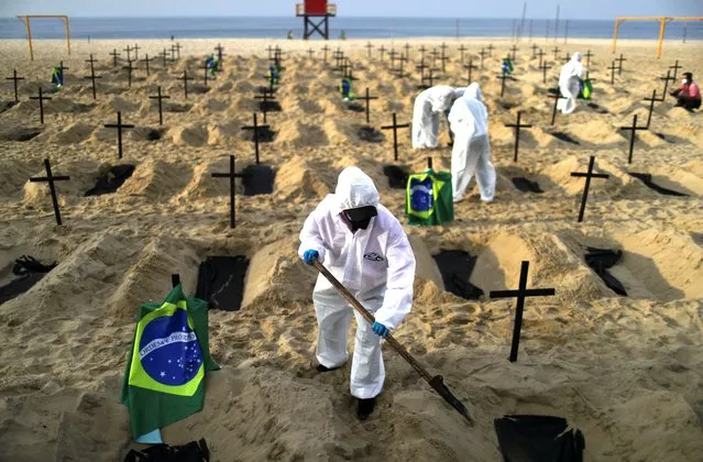 Activists of the NGO Rio de Paz in protective gear dig graves on Copacabana beach to symbolise the dead from the coronavirus disease (COVID-19) during a demonstration in Rio de Janeiro, Brazil, June 11, 2020. (Photo by Pilar Olivares/Reuters)