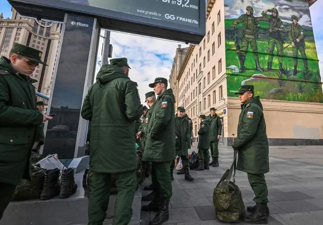 Russian soldiers wait for their departure as they stand near a mural depicting Russian servicemen wearing «Z» symbol armbands, close to the Paveletsky railway terminal, in central Moscow on October 16, 2022. (Photo by Yuri Kadobnov/AFP Photo)