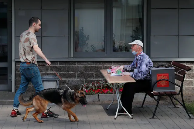 A member of a local electoral commission talks to a man holding a dog at an outdoor polling place during a seven-day vote on constitutional reforms in Saint Petersburg, Russia on June 25, 2020. (Photo by Anton Vaganov/Reuters)