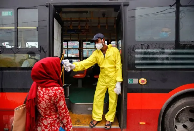 A bus conductor checks the temperature of a passenger before getting inside the bus as restrictions on public transportation are eased by the government following the outbreak of the coronavirus disease (COVID-19), in Kathmandu, Nepal on July 14, 2020. (Photo by Navesh Chitrakar/Reuters)