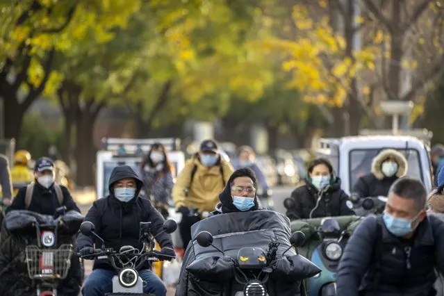 Commuters wearing face masks ride along a street in Beijing, Wednesday, November 16, 2022. (Photo by Mark Schiefelbein/AP Photo)