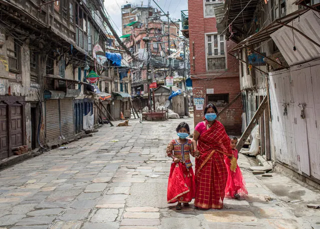 Women in red attire walk to worship Lord Shiva (Hindu god of creation and destruction) to mark the Teej festival amid the coronavirus pandemic lockdown in Kathmandu, Nepal, 21 August 2020. The majority of women usually celebrates Teej festival at their homes but some managed to visit the Pashupati temple and Bagmati River, despite authorities imposing a complete lockdown in Kathmandu valley for a week. The Teej festival is celebrated by Nepalese women to wish a long and prosperous life to their husbands. Those who are not yet married, pray to get a good husband by fasting for a whole day. (Photo by Narendra Shrestha/EPA/EFE)