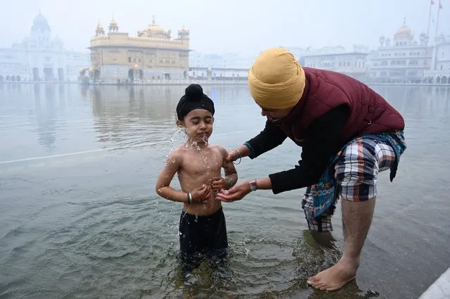 A young Sikh devotee takes a bath in the holy Sarovar (pool) on the occasion of the birth anniversary celebrations of the tenth Guru of the Sikhs Guru Gobind Singh at the Golden Temple in Amritsar on December 29, 2022. (Photo by Narinder Nanu/AFP Photo)