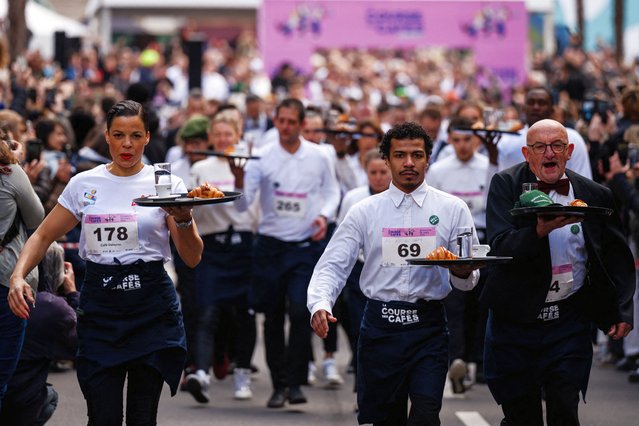 Waiters and waitresses in work outfits compete in a traditionnal “Course des cafes” (the cafes' race), in front of the City Hall in central Paris, on March 24, 2024. Around 200 participants gathered to compete in the 2km race around Paris' Marais district single-handedly carrying a tray bearing a coffee, a glass of water and a croissant. Founded in 1914, this is the first edition of the race after a 13-year hiatus. (Photo by Dimitar Dilkoff/AFP Photo)
