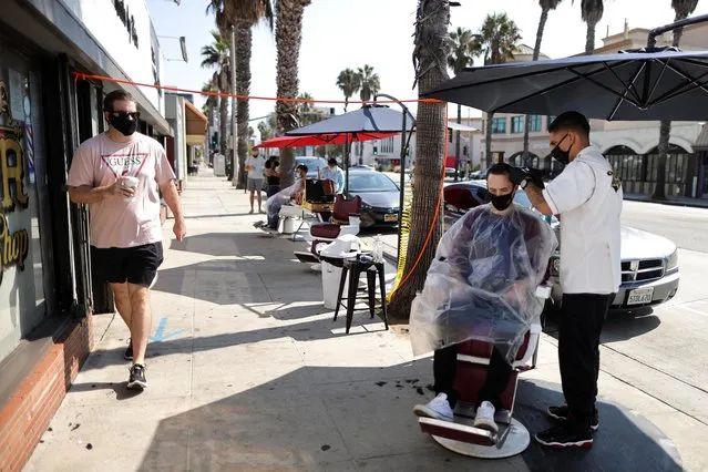 Keith Huerta, 30, cuts the hair of Nick Parr, 25, on the street outside Active Barbers, amid the global outbreak of the coronavirus disease (COVID-19), in Santa Monica, California, U.S., September 2, 2020. (Photo by Lucy Nicholson/Reuters)