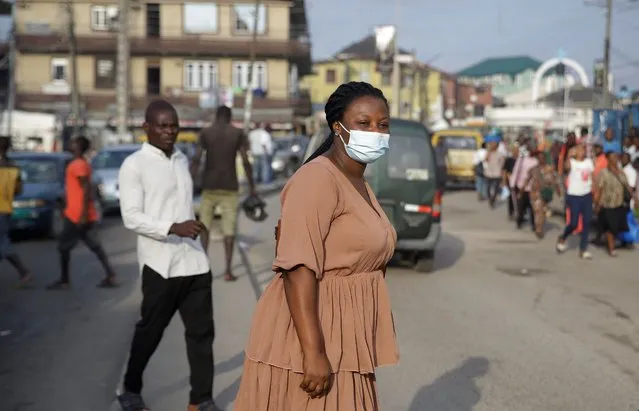 A woman wearing a face mask to protect against coronavirus crosses the main road in Lagos, Nigeria, Monday September 28, 2020. Nigeria officials recently reopened worship centres and resumed international flights following months of closure to curb the spread of coronavirus. (Photo by Sunday Alamba/AP Photo)