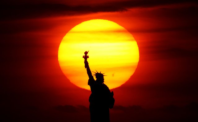 The sun sets behind the Statue of Liberty on May 7, 2025, in New York City. (Photo by Gary Hershorn/Getty Images)