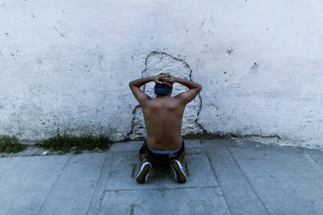 In this May 28, 2015 photo, a suspected gang member who was found out of breath on a bed following a chase by police, faces a wall with his hands on his head, in San Salvador, El Salvador. (Photo by Manu Brabo/AP Photo)