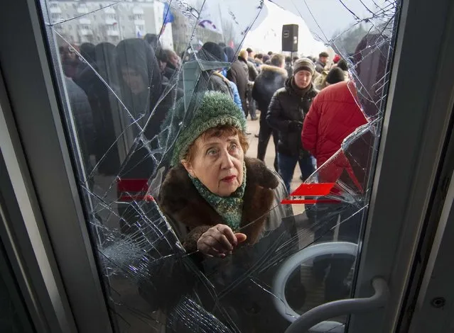 A woman looks through a damaged door as pro-Russian demonstrators hold a rally outside the regional government building in Donetsk, in this March 3, 2014 file photo. (Photo by Reuters/Stringer)