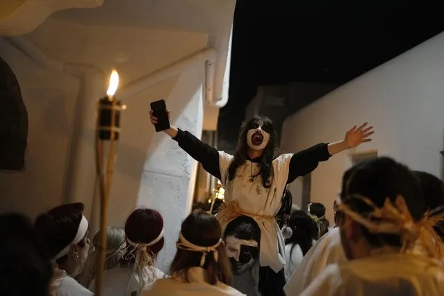 A woman shouts, as men and women with faces painted wear white sheets and hold torches on long poles, take part at the Torch Parade (Lampadiforia) on the Aegean Sea island of Naxos, Greece, late Saturday, February 25, 2023. The first proper celebration of the Carnival after four years of COVID restrictions, has attracted throngs of revellers, Greek and foreign, with the young especially showing up in large numbers. (Photo by Thanassis Stavrakis/AP Photo)
