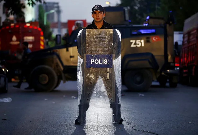 A Turkish police officer stands behind his shield as he secures the scene of a blast in Istanbul, Thursday, October 6, 2016. A bomb placed on a motorcycle has exploded near a police station Thursday, wounding several people, Vasip Sahin, the governor for Istanbul, said. Turkish authorities have banned distribution of images relating to the explosion within Turkey. (Photo by Emrah Gurel/AP Photo)