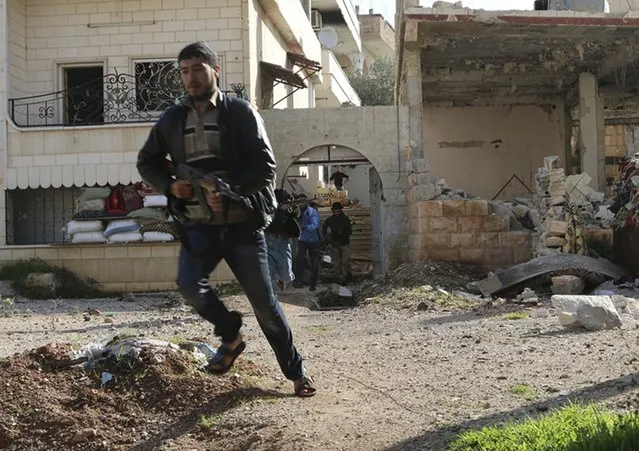 A rebel fighter carries his weapon as he runs near the frontline against forces loyal to Syria's President Bashar al-Assad in al-Manshiyeh neighbourhood in Deraa December 7, 2014. Picture taken December 7, 2014. (Photo by Wsam Almokdad/Reuters)