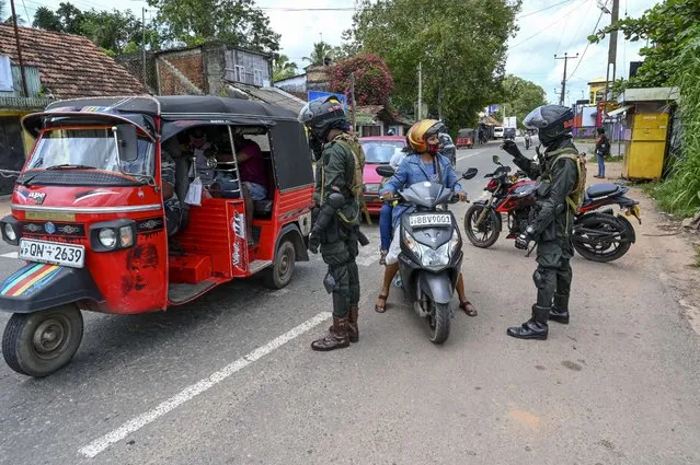 Security personnel stop motorists at a checkpoint in Divulapitiya on the outskirts of the Sri Lankan capital of Colombo on October 4, 2020, as police imposed a curfew on the towns of Minuwangoda and Divulapitiya following the discovery of a coronavirus patient, the first case reported from the community after several weeks. Sri Lanka has reported 3,395 cases with 13 deaths since the first COVID-19 case was detected in the island on January 27. (Photo by Ishara S. Kodikara/AFP Photo)